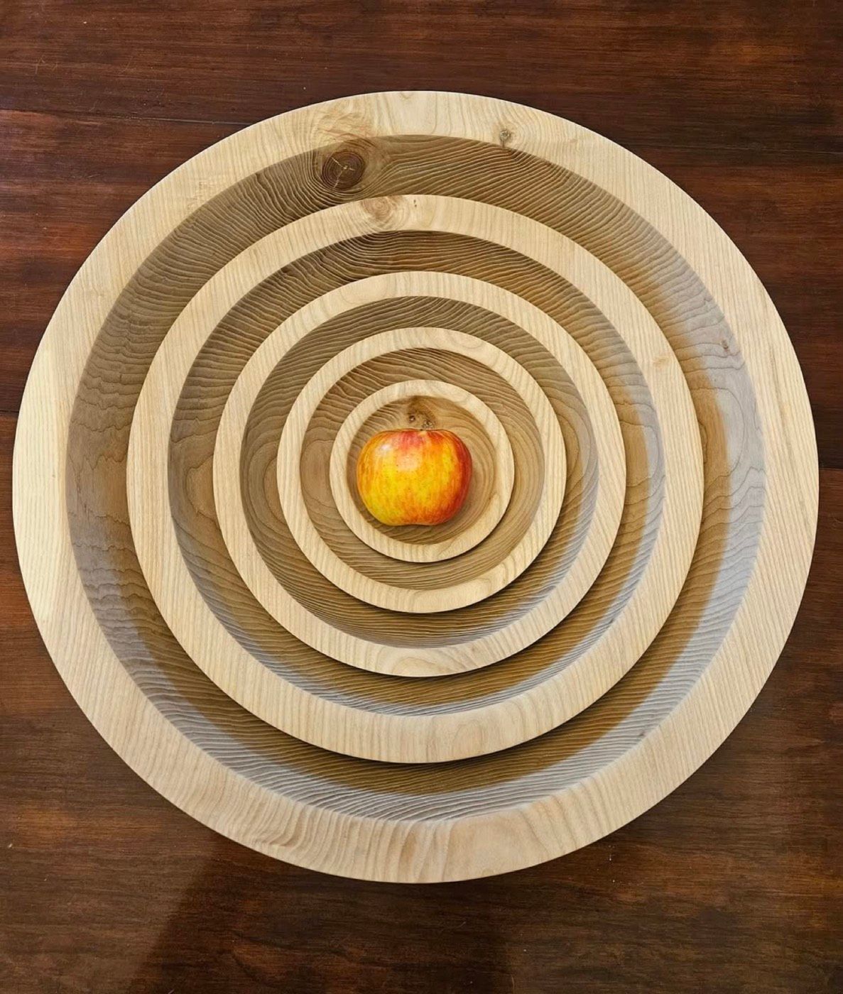 A nested set of ash bowls cored from one blank, with an apple in the smallest
